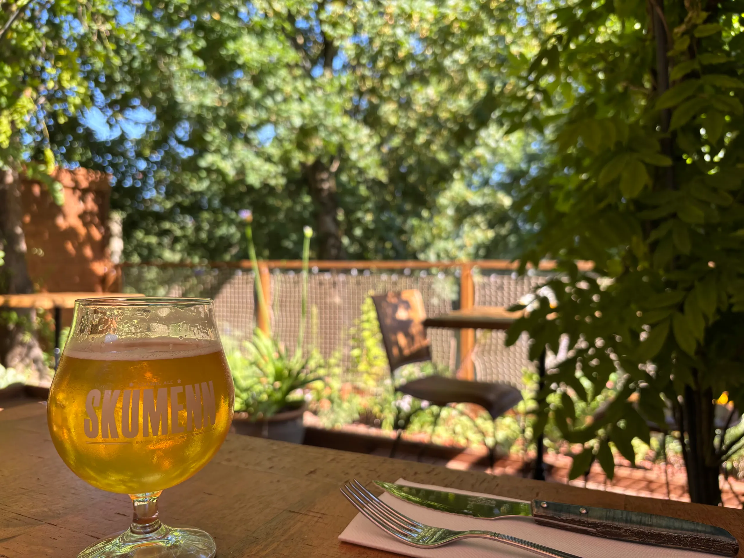 Verre de bière sur une table de la terrasse, entourée de verdure